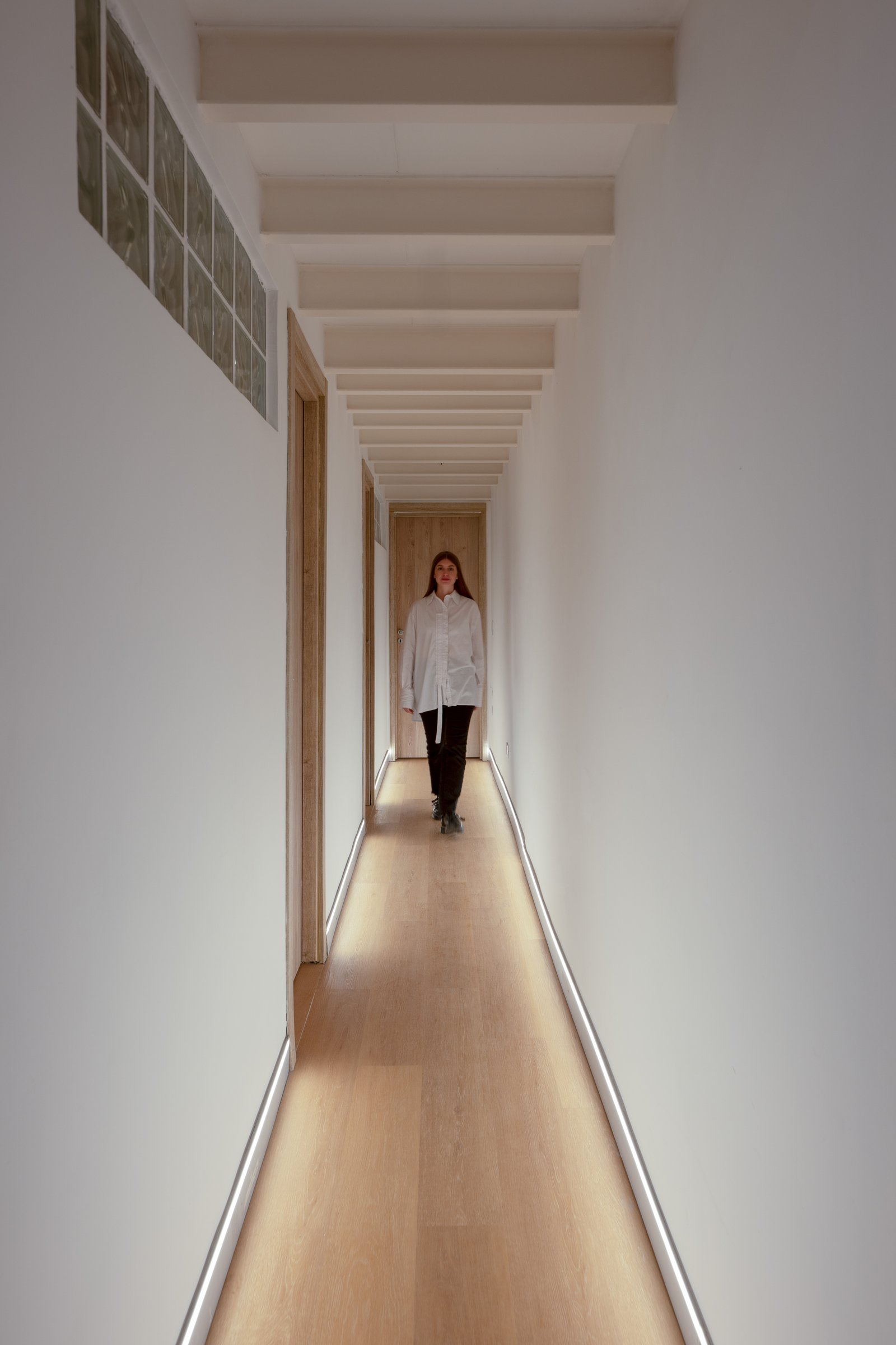 corredor longo e iluminado com vigas expostas — projeto Casa Gainza, por Estudio Plats, em Caballito